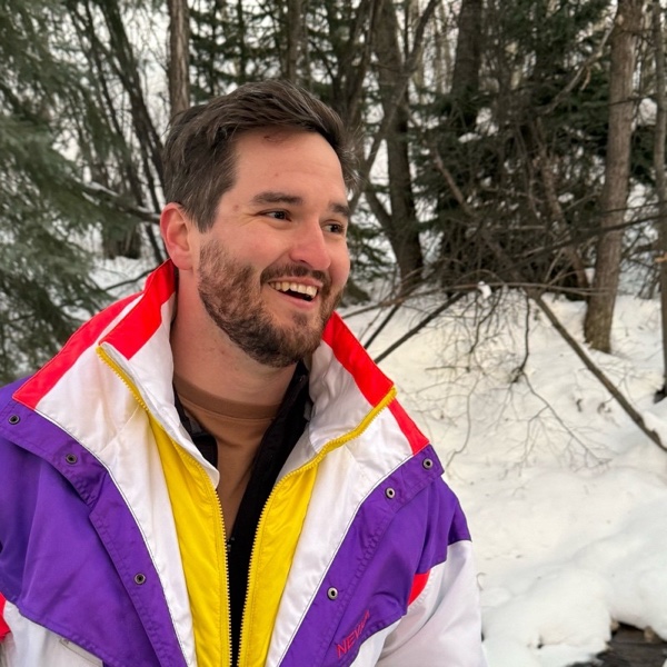 Connor laughing in the snow in a bright ski jacket