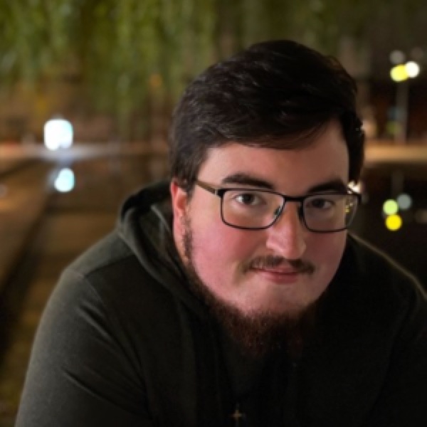 Cooper in glasses, lit by city lights at night
